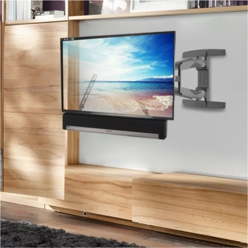 טלוויזיה בעלת מסך שטוח מותקנת על מתקן תלייה לסאונד בר על יחידת קיר מעץ, עם סאונד בר ממוקם מתחתיה. מסך הטלוויזיה מציג סצנת חוף שלווה.